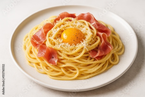 Creamy pasta dish featuring prosciutto, grated cheese, and a rich egg yolk with a focused background