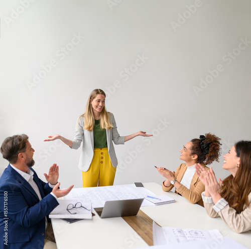 Happy business people applauding for female architect and celebrating her success in office during meeting