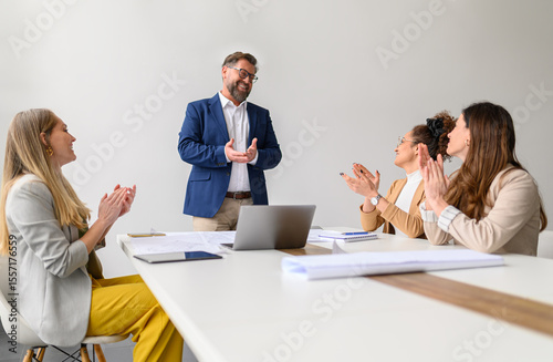 Happy business professionals applauding for male architect and celebrating his success in office during meeting
