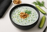 Chilled refreshing tahini soup garnished with nuts served in a dark bowl