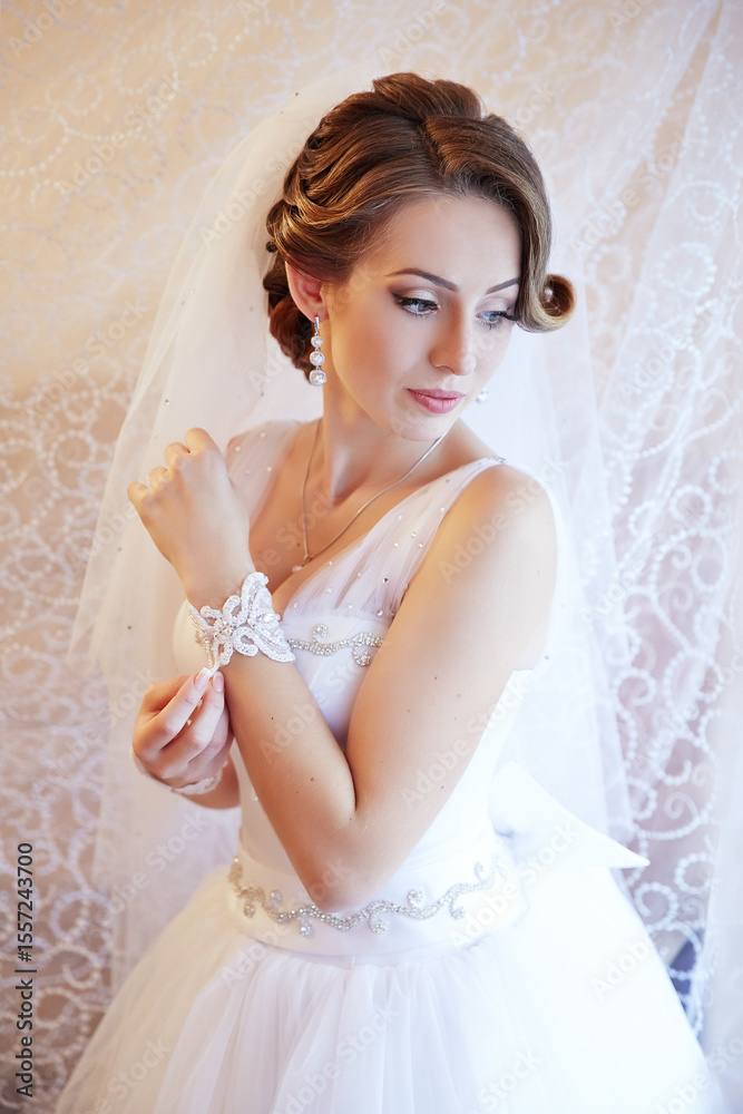 A woman in a white dress is wearing a white veil and a white bracelet A woman in a white dress is wearing a white veil and a white bracelet