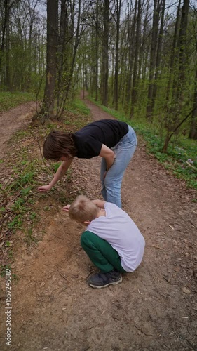 A mother and her son with a hearing aid enjoy a peaceful forest walk, sharing a genuine moment of connection and rehabilitation in nature. Authentic, heartwarming family bonding