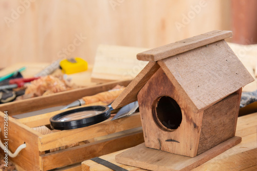 Wooden bird house DIY from small piece of leftover wooden after finished furniture, small business or freelance carpenter, Stack of wood dust on background, sawdust in Carpentry Studio shop