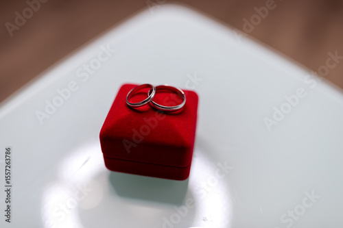 Rings on a red velvet box. Two silver wedding rings are placed elegantly on a red velvet ring box, showcasing romance and commitment.