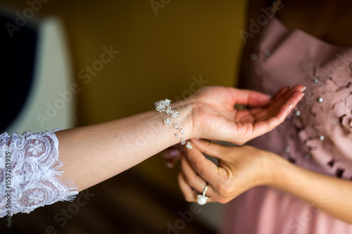 Friends swapping a bracelet. Two friends share a special moment as one helps the other wear a stunning bracelet during a joyful occasion.