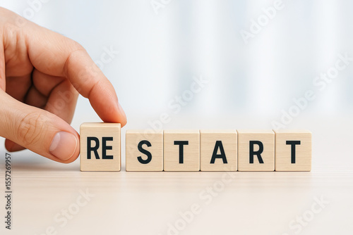 Hand adjusting wooden blocks that spell word RESTART, symbolizing new beginnings and fresh starts, conveys sense of motivation and change