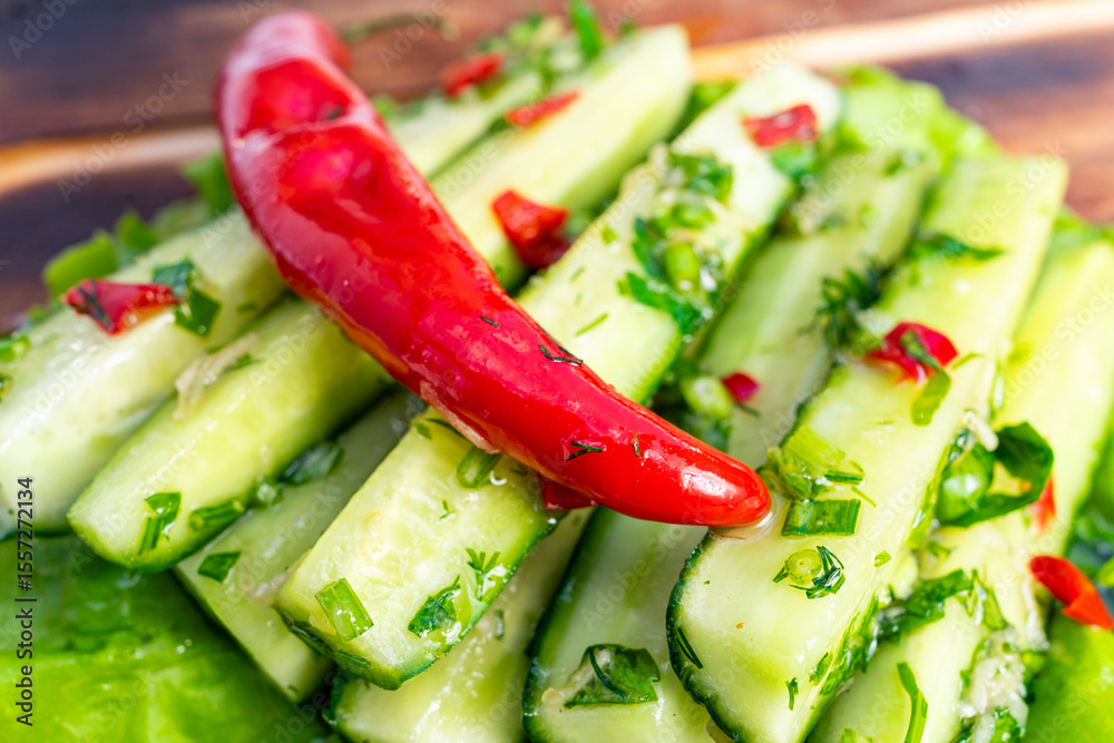 Fresh cucumber salad with red chili and herbs garnished on a wooden platter Fresh cucumber salad with red chili and herbs garnished on a wooden platter