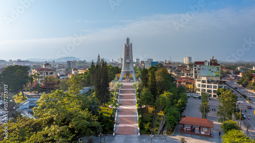 Backlit aerial view of Doi Can temple, with long shadows and sun glare, showcasing urban life under bright sunlight.