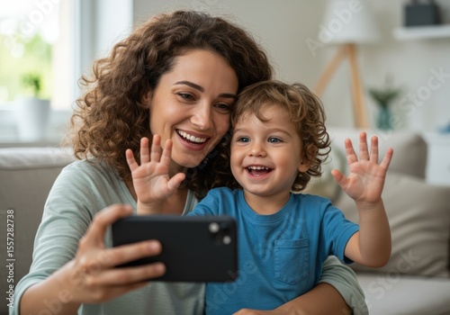 A loving mother and son share a joyful moment, waving during a video call.