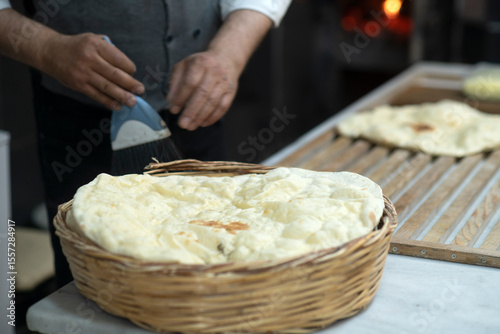Male hands brushing freshly baked famous flat bread called lavaş in front of a wood burning fire in a traditional bakery in Turkey