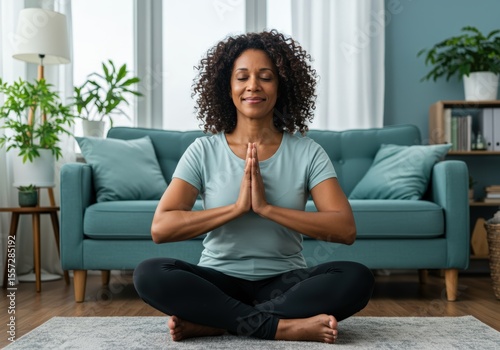 A serene black woman meditates in her living room, promoting wellness and peace.