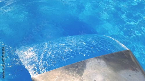 Video footage of blue clear water falling into a blue pool.