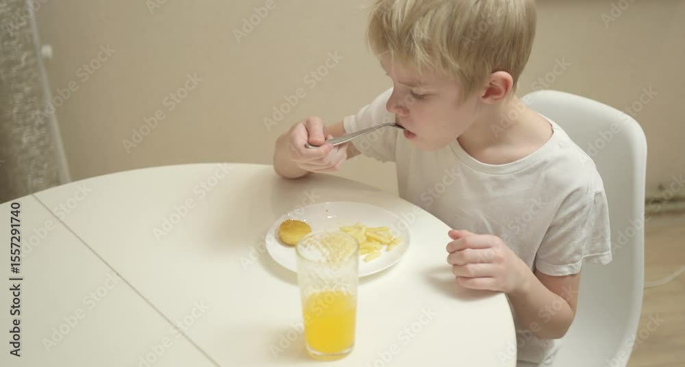 A little boy enjoys his breakfast at the kitchen table in a natural, authentic moment. Candid emotions, messy hair, and genuine childhood joy make this scene heartwarming A little boy enjoys his breakfast at the kitchen table in a natural, authentic moment. Candid emotions, messy hair, and genuine childhood joy make this scene heartwarming