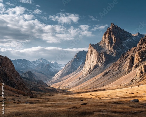 Majestic mountain range with valley, sunlight, and dramatic clouds