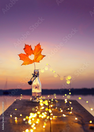 Seaside Romance: Glass Bottle and Autumn Leaf at Sunset