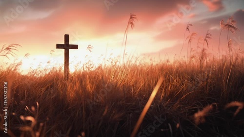 Lone cross standing in a field at sunset