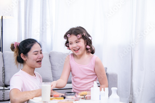 Kids, cosmetic, child, beauty, skincare, A girl and her mother laugh together while playing with makeup items, showing fun, love, and joyful bonding in a family selfcare moment at home