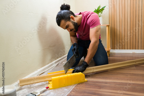 Handyman cutting wood trim using mitre box and saw for home renovation