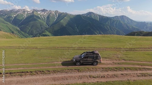Suv traveling along dirt path in lush mountain setting, showcasing rugged adventure and breathtaking natural landscape with panoramic views