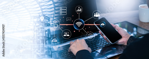 Businessman Hand Using Smartphone and Laptop with Technology Icon Overlay, Digital Connection Concept for Innovation, Cloud Computing, Wireless Network, and Modern Communication Background