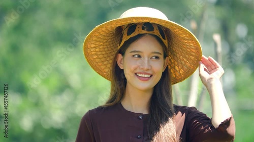 Smiling portrait of young Asian woman wearing traditional hat, smallholder farmer. 4k