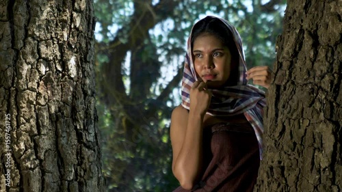 Portrait Asian woman smiling with Thai loincloth covers head standing near a big tree in the forest