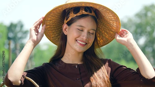 Smiling portrait of young Asian woman wearing traditional hat, smallholder farmer. 4k resolution