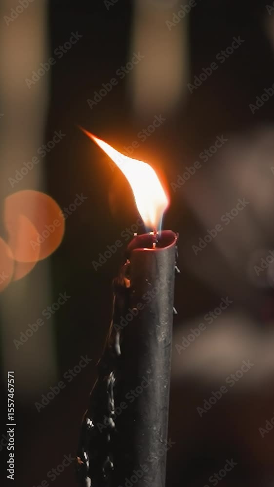 Flickering flame of black candle sets mood for woman. Burning candles illuminate space where young woman in blanket drinks wine. Evening atmosphere of romance