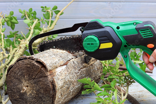 mini chainsaw cutting a wooden log