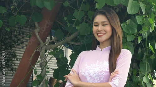 Beautiful Asian woman with long hair in pink Vietnamese dress smiling and looking at the camera, 4K video