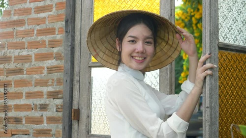 Smiling portrait Vietnamese woman wearing white national costume and hat poses and looks at the camera, video 4K