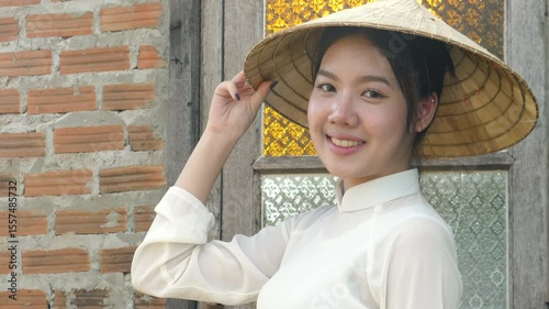 Smiling portrait Vietnamese woman wearing white national costume and hat poses and looks at the camera, video 4K