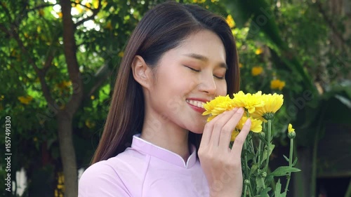 Beautiful Asian woman with long hair in pink Vietnamese dress smiling and looking at the camera, 4K video.