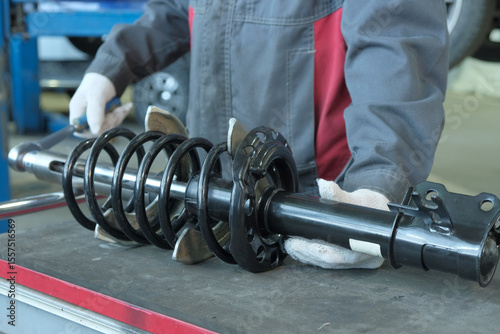 Car maintenance at a car service center. An auto mechanic performs car suspension repairs.Preparing the shock strut for replacement on the car.