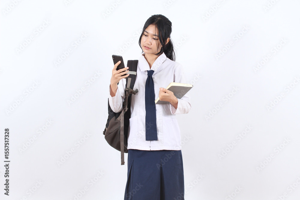 Asian teenage girl with long hair wearing school uniform and bag looking smart phone Asian teenage girl with long hair wearing school uniform and bag looking smart phone