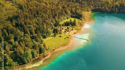 Alpsee lake with turquoise waters surrounded by Bavarian Alps, near Schloss Hohenschwangau and the iconic Neuschwanstein Castle. Captured from drone on a clear summer day