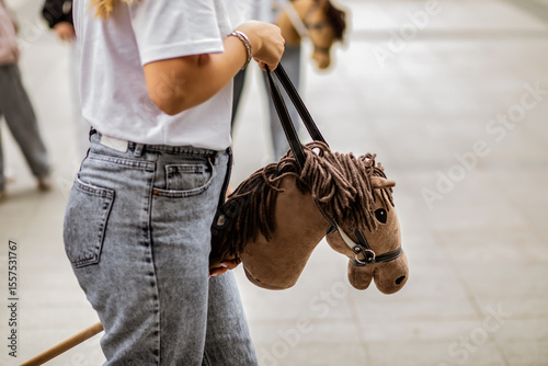 Young woman hobby horse riders jumping with stick toy horse