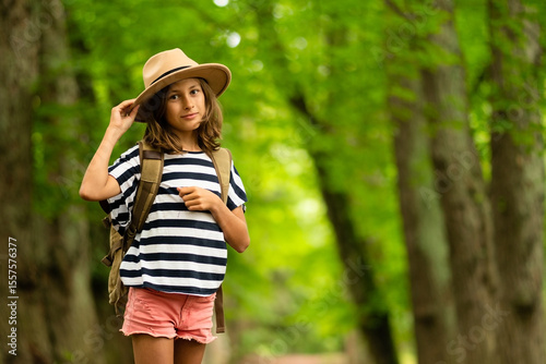 Youthful adventurer pauses mid-trail, glancing back with anticipation. Packed backpack signals beginning of memorable forest exploration in golden sunlight.