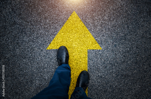 Man standing on asphalt road with the arrow sign