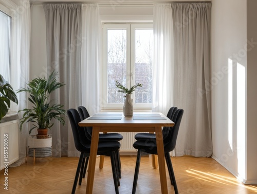 A table with four chairs and a vase of flowers in the middle. The table is surrounded by a window and curtains