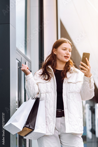 Woman enjoying shopping while checking her phone for discounts and sales outside a store