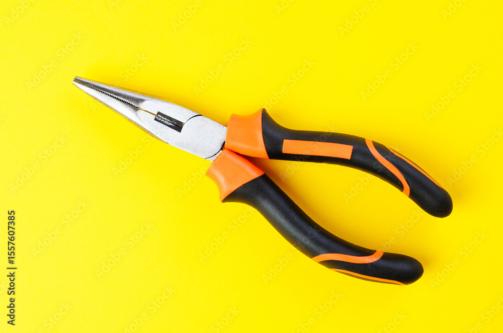 Obraz premium Close-up of metal pliers on vibrant yellow background with sharp details