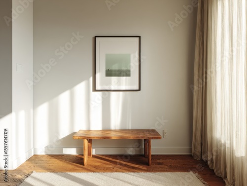 A wooden bench is in a room with a white wall. A picture is hanging on the wall