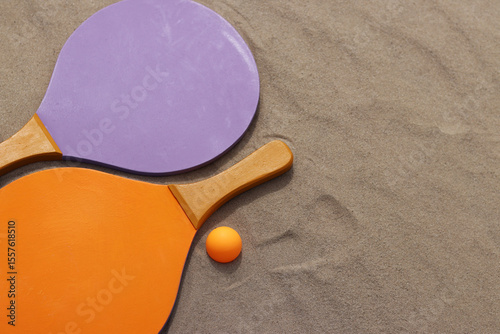 Bright wooden rackets for outdoor games. Summer outdoor games. Summer sports and games concept. Beach tennis rackets and ball on sand. Active lifestyle, games and sports. Beach tennis set. Close-up