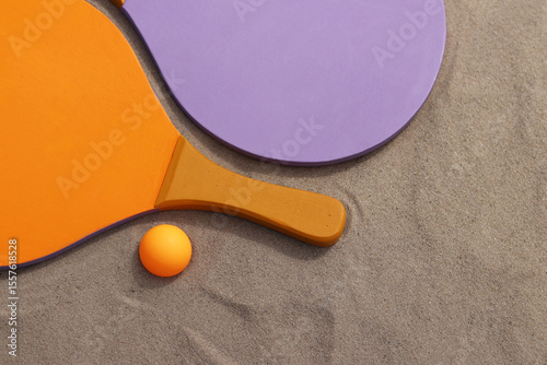 Bright wooden rackets for outdoor games. Summer outdoor games. Summer sports and games concept. Beach tennis rackets and ball on sand. Active lifestyle, games and sports. Beach tennis set. Close-up