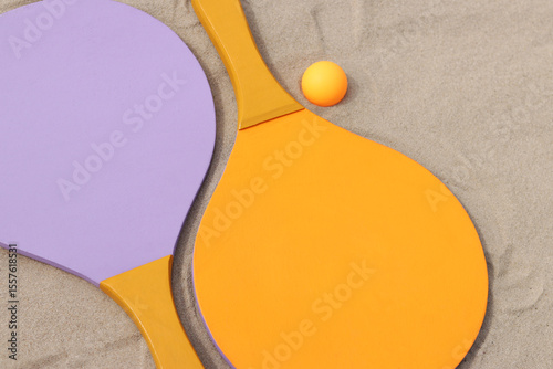Bright wooden rackets for outdoor games. Summer outdoor games. Summer sports and games concept. Beach tennis rackets and ball on sand. Active lifestyle, games and sports. Beach tennis set. Close-up