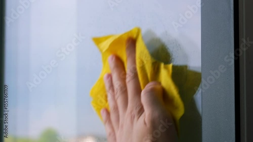 A man wipes a dirty window in a house with a rag.
Cleaning the apartment.
A cleaner with a rag wipes dirt and dust on the window