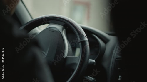 Back view of car buff driving, skillfully turning steering wheel to execute smooth turn, blurred street scene visible through window, capturing driver focus, control and urban commute vibe