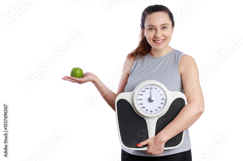 Smiling woman holding weight scale and green apple for healthy lifestyle