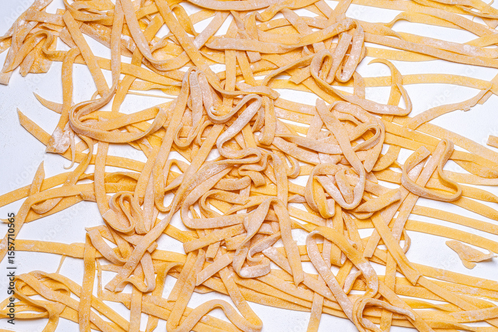 Obraz premium Handmade raw pasta, spaghetti on a white table. Background with raw spaghetti texture. Close-up, top view.